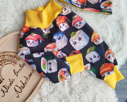 Beispielbild einer Pumphose. Gelbes Bündchen am Bauch und an den Beinen. Muster der Pumphose: schwarzer Hintergrund mit unterschiedlichen lächelnden Comicartigen Sushis.